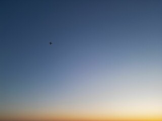 Airplane flying in the blue sky at sunset