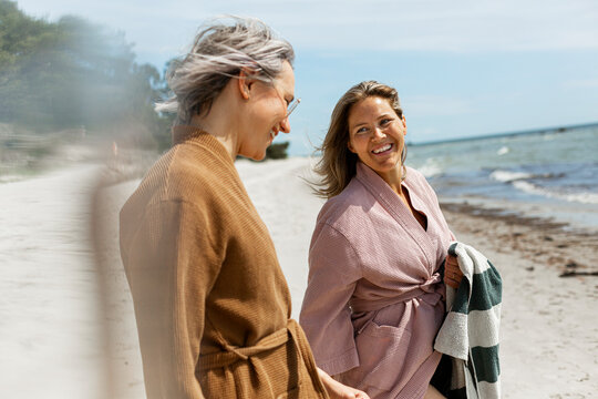 Happy mature female friends spending leisure time at beach on weekend