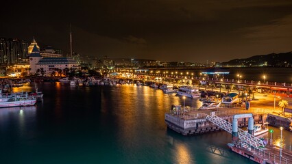 Stunning night-time landscape of a harbor with a fleet of boats illuminated by lights