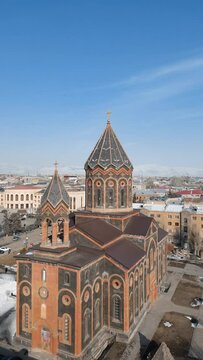 Rotating view of All Saviors Church dome with a cross against blue sky in Gyumri, Armenia