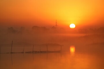 the sun rises over the water near a body of water