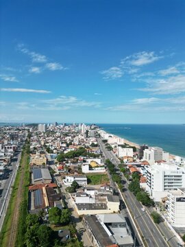 Aerial the blue sea and residential buildings across the shoreline. Macae, Rio de Janeiro, Brazil.