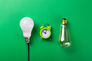 Flatlay Clock with light bulb, calculator on a green background. Minimalism. Top view. Concept ecology, save planet earth, idea, save energy, economy, saving. Earth day..