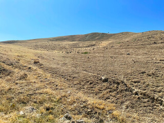 Sandy field in the mountains against a background of bright blue sky