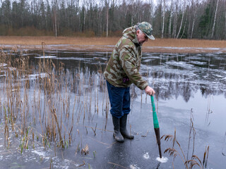 winter angler checks the strength and thickness of the ice