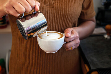 Barista pouring milk into coffee making a cappuccino. Barista making cappuccino,Professional bartender preparing coffee drink