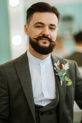 portrait of smiling groom with beard in gray color suit