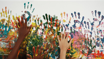 Happy diverse student hand placed on colorful stained wall. Closeup of multicultural hand or...