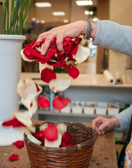 Woman's hands dropping rose petals into a wicker basket
