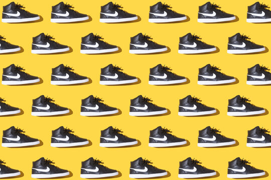 Pattern of black NIKE boot sneakers with the logo in white, on a yellow background. Concept of sneakers, basketball, retro, michael jordan, fashion, collection and casual.