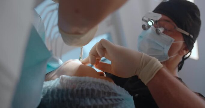 Portrait of the dental surgeon doing the surgery with assistant in dental clinic