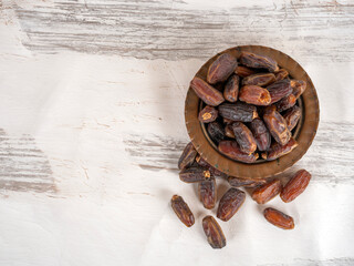 Copper bowl full of  dry date fruits, top view image of traditional classic copper bowl full of  dry date fruits. white painted wooden background. Copy space. Iftar snack, starter.