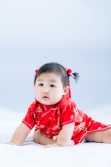 Chinese New Year concept, cute happy little girl in Chinese dress sitting in white living room. Cute Asian baby sitting in white living room, Chinese New Year concept.