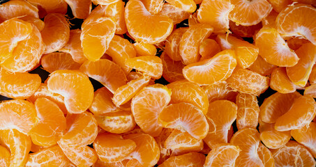 Peeled tangerines on a black background. Slices of tangerine or mandarin fruit close up