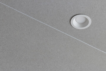 Modern minimal recessed electric white light fitting in textured grey interior ceiling