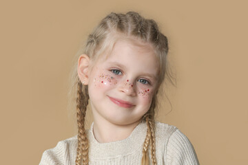 Portrait of cute little blonde girl with boxer braids and glitters om face