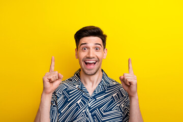 Photo of impressed ecstatic man with bristle dressed blue clothes indicating at poster empty space isolated on yellow color background - obrazy, fototapety, plakaty