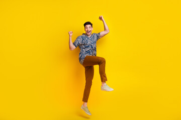 Fototapeta na wymiar Full length photo of overjoyed man dressed print shirt brown trousers raising fists up win gambling isolated on yellow color background