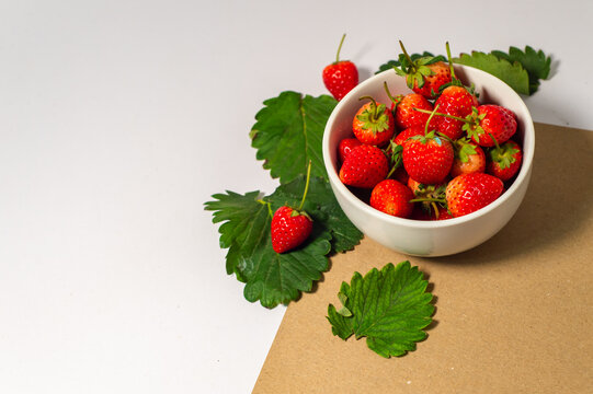 ripe red strawberries A white bowl filled with juicy, ripe red strawberries. Strawberries on brown background, white table, fresh strawberries healthy food pictures