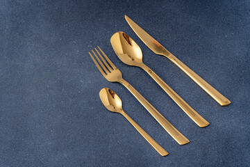 Set of cutlery made of gold metal. Fork, spoon, knife, teaspoon