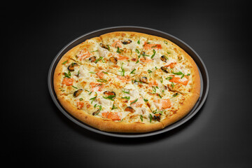 Pizza with seafood: salmon, mussels, shrimp. On a black background.
