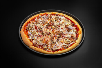Meat pizza with meat, mushrooms, onions and cheese. On a black background.