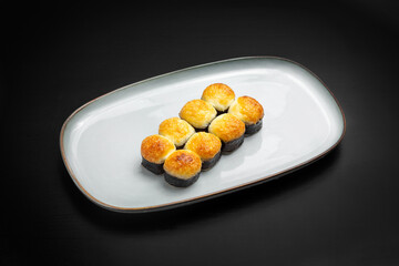 Sushi, baked rolls. On a black background.