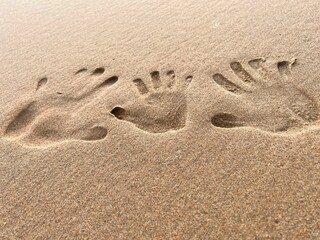 Fototapeta na wymiar Closeup of three human handprints in beach sand