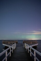 the pier under the aurora lights by the ocean on a clear night