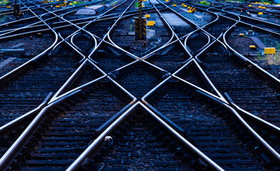 Reflecting symmetrical rails with blue hour twilight. Railway tracks, switches and crossings at a...