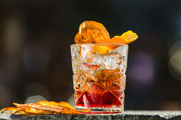 Delicious old fashion cocktail in the etched glass with ice and orange slices. Shallow dof.
