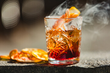 Delicious old fashion cocktail in the etched glass with ice and orange slices. Shallow dof.