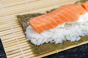 preparing sushi at home, homemade gourmet salmon roll