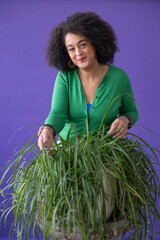 Studio portrait of woman inspecting potted plant