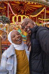 Portrait of female tourists in hijabs in front of merry-go-round