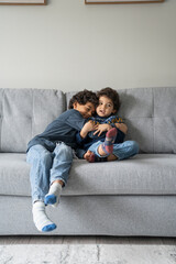 Brothers (2-3, 6-7) hugging on sofa at home