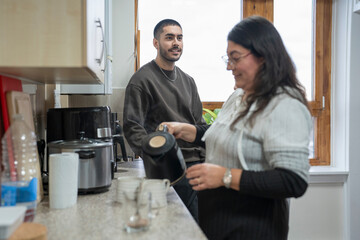 Smiling mother and son preparing tea at home