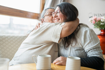 Senior mother and mature daughter hugging at home