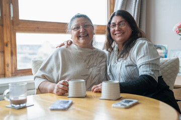 Portrait of senior mother and mature daughter drinking tea at home