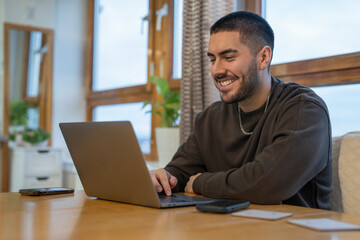 Smiling young man working on laptop at home