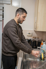 Young man washing dishes at home