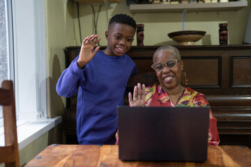 Grandmother with grandson using laptop at home 
