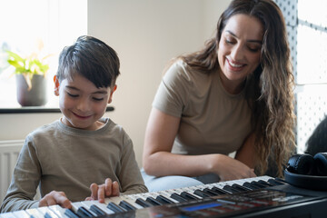 Mother and son (6-7) playing music keyboard at home - obrazy, fototapety, plakaty