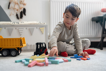 Boy (6-7) sitting on floor and playing with toys