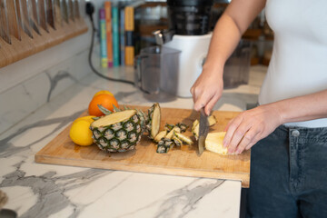 Woman slicing fruit in kitchen, midsection