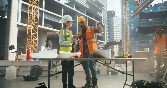 Technical Inspector Interviewing a Construction Manager on Behalf of an Occupational Health and Safety Commission. Female Specialist Using a Tablet Computer to Question a Construction Worker