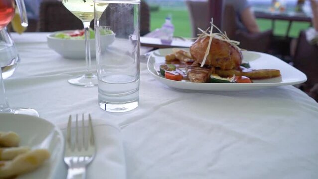 Croatian gastronomy meat and corn bread with brown sause and vegetables in an expensive restaurant terasse with wine glasses