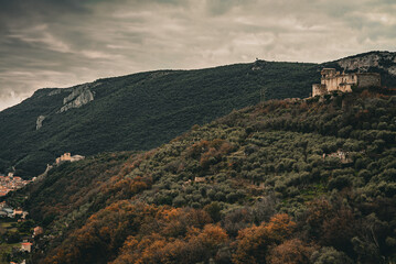 Fototapeta na wymiar A landscape view, old film style color correction, an old medieval castle on top of the mountain in the middle of forest in Pietra Ligure, Italy