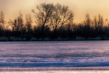 North-eastern European river after frosty winter. Porous ice began to melt, river is swollen, state of ice week before ice break (ice-boom). Aurora, sunrise colors on a spring moning