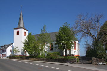 Fototapeta na wymiar Gothic St. Luzia church with white bell tower in Habscheid village, Eifel region in Germany